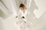 Person in weißem Outfit tanzt auf einem hellen Boden