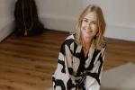Frau, die auf dem Boden sitzt, lächelt in gemusterter Robe