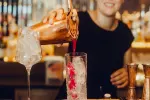 Barkeeper gießt einen Cocktail in ein Glas mit Eis