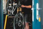 Person hält ein Fahrrad in einer Werkstatt