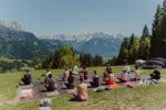 Menschen meditieren im Freien mit Bergen im Hintergrund
