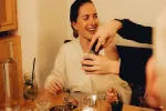 Eine lachende Frau an einem Tisch, an dem Getränke serviert werden.