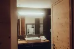 modernes Badezimmer mit Waschbecken, Spiegel und Holztür