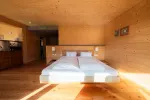 helles Schlafzimmer mit Holzwand und Doppelbett