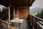 Holzbalkon mit Tisch und Stühlen mit Blick auf eine hügelige Landschaft