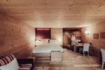 Holzverkleideter Raum mit Bett, Schreibtisch und Sitzbereich