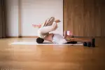 Person übt Yoga auf einer Matte in einem Studio mit Holzboden