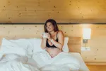 Frau im Bett mit Handy, gemütliche Zimmergestaltung