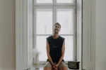 Person sitzt vor einem Fenster, lässige Kleidung