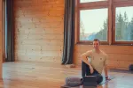 Person sitzt auf dem Boden in einem Holzraum mit großen Fenstern