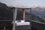 Eine ruhige Bergsicht von einem modernen Balkon mit einem Bett, das mit transparenter Stoff ausgestattet ist