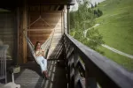 Person entspannt in einer Hängematte auf einem Holzbalkon
