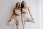 Zwei Frauen in weißen Outfits nehmen eine verspielte Pose ein