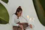 Frau sitzt auf dem Boden mit einer Pflanze im Hintergrund