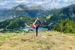 Person übt Yoga auf einem Berg mit Blick auf einen See