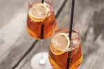 Zwei Gläser mit orangefarbenen Getränken und Zitronenscheiben
