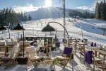 Sonnenbeschienene Terrasse mit Blick auf die Pisten im Schnee.
