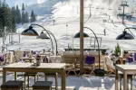 Bergrestaurant mit Tischen und Skipisten im Hintergrund