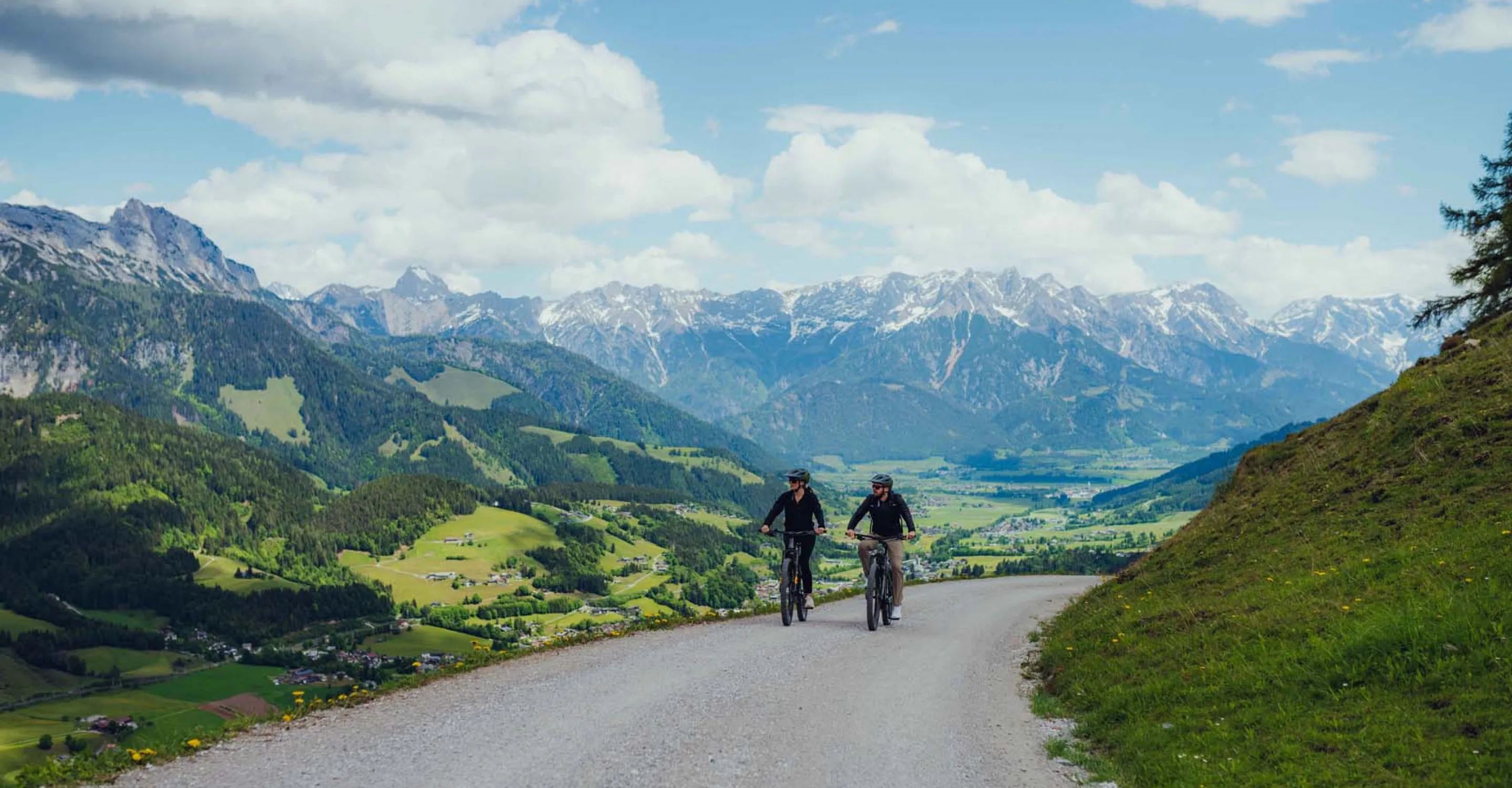 Zwei Radfahrer auf einem Weg mit Bergen im Hintergrund