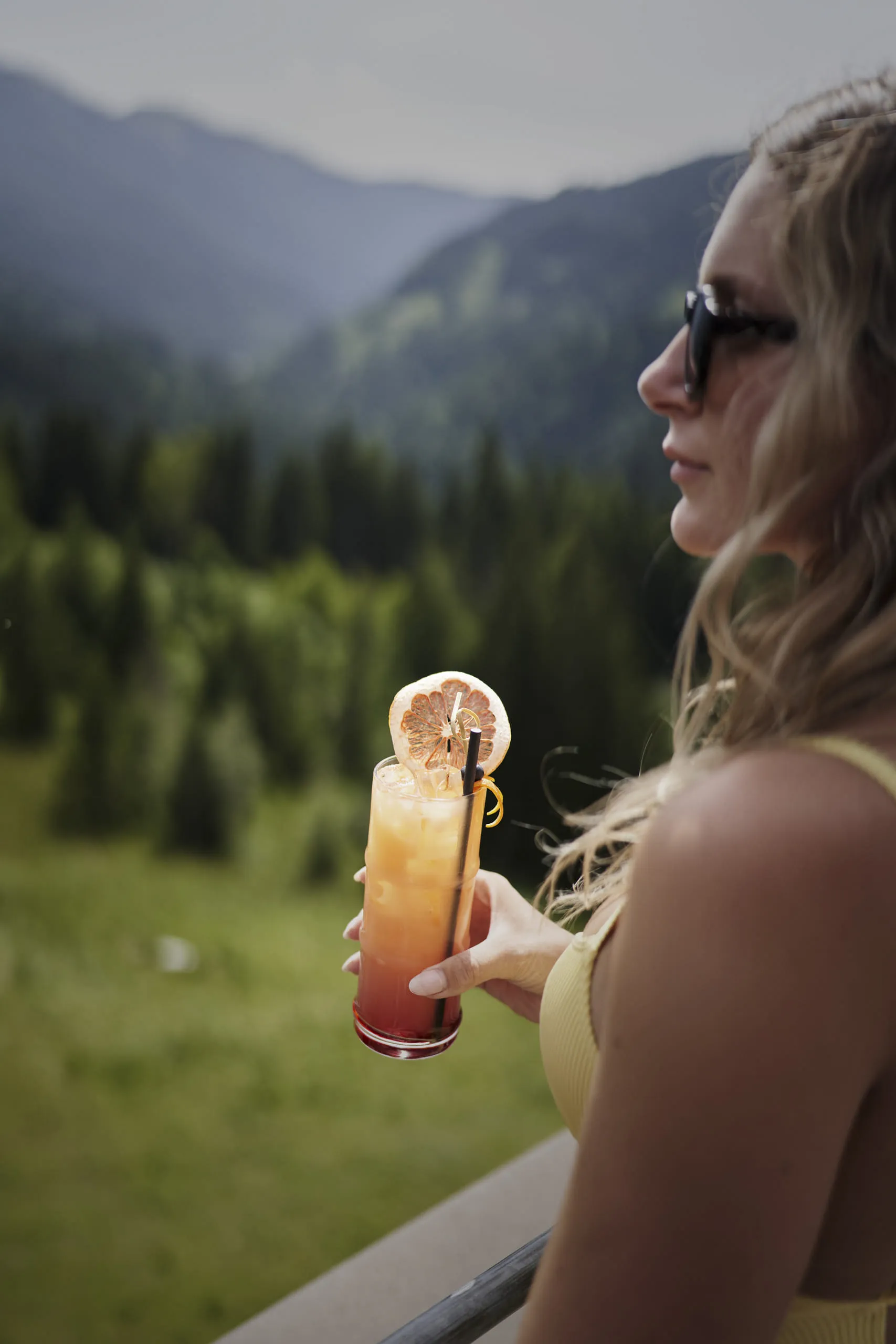 Frau trinkt Cocktail am Rooftop Pool