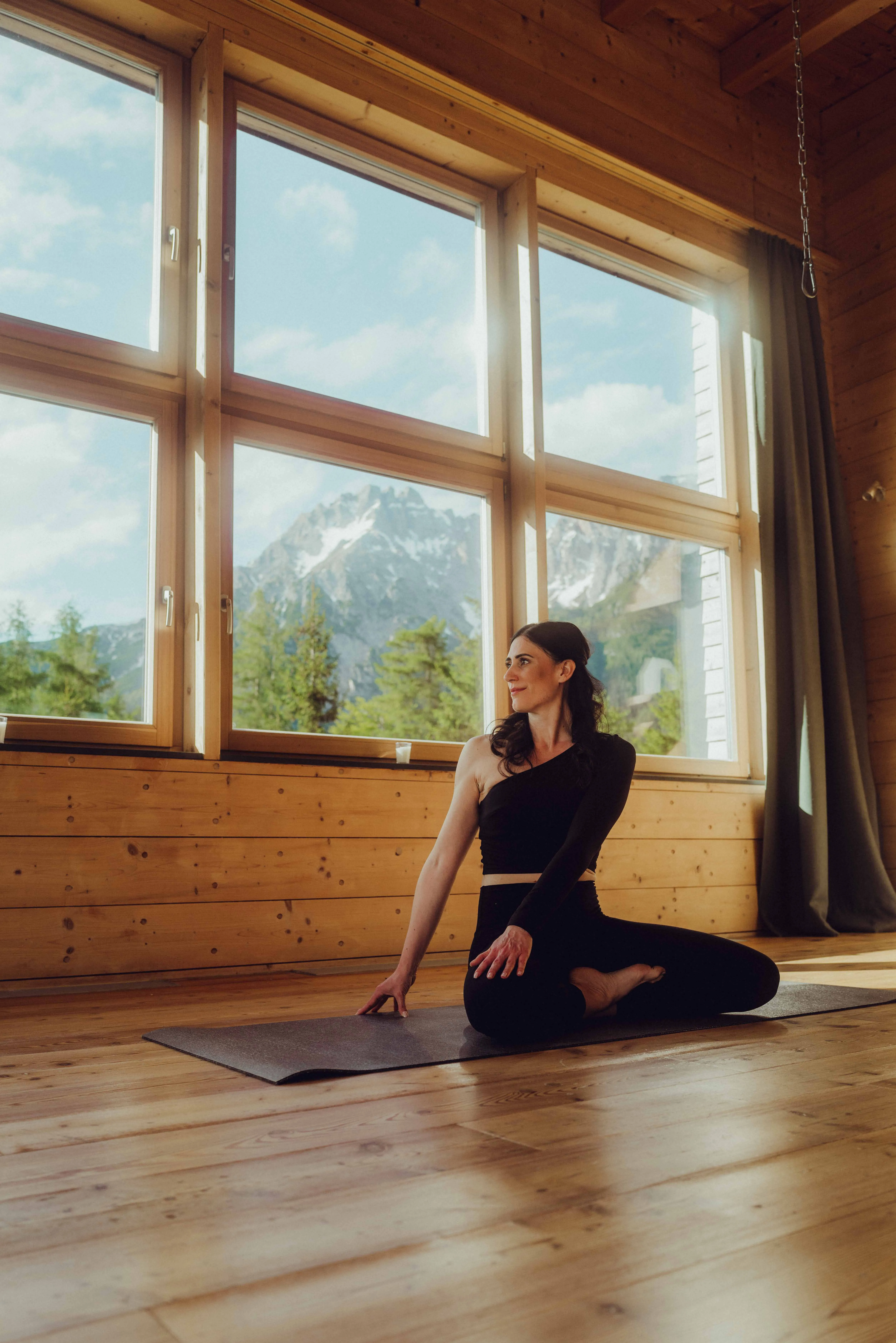 Frau praktiziert Yoga im Yogaraum aus Holz
