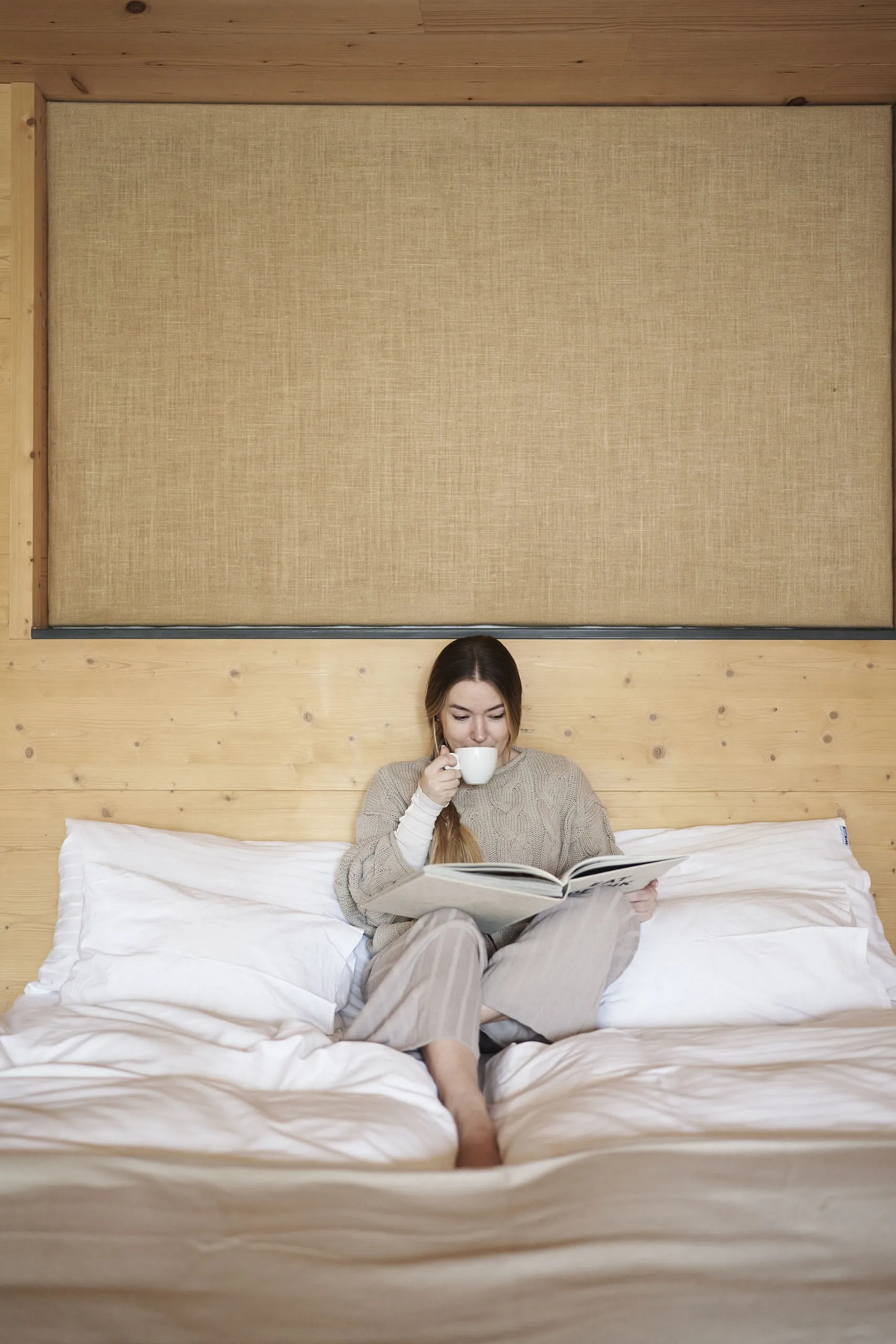 Frau trinkt Kaffee im Hotelbett
