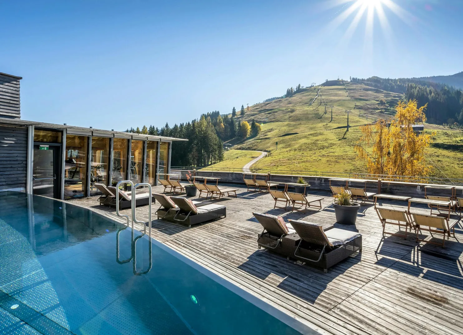 Bunte Herbstbäume am Berggipfel, Pool im Vordergrund