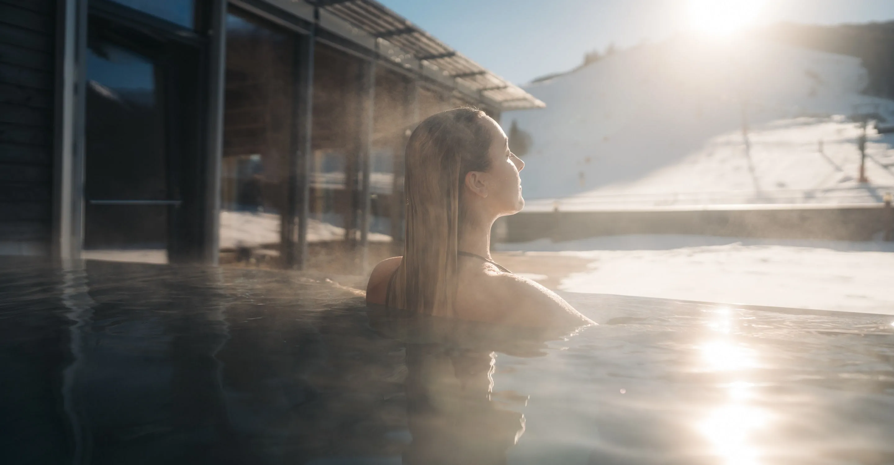 Frau in einem Außenwhirlpool mit Schnee im Hintergrund