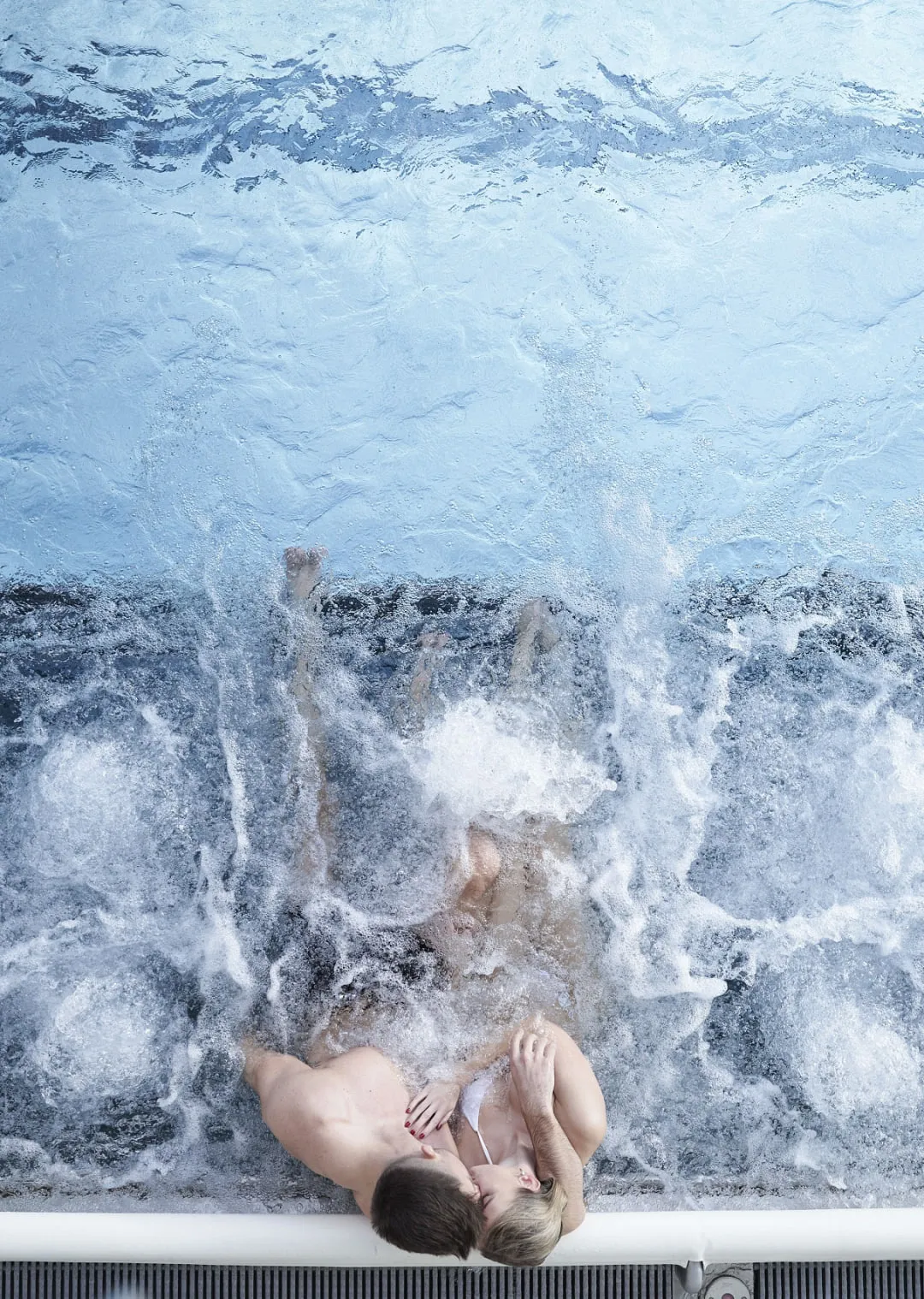 Paar im Pool, umgeben von Wasser mit Spritzern, entspannende Atmosphäre