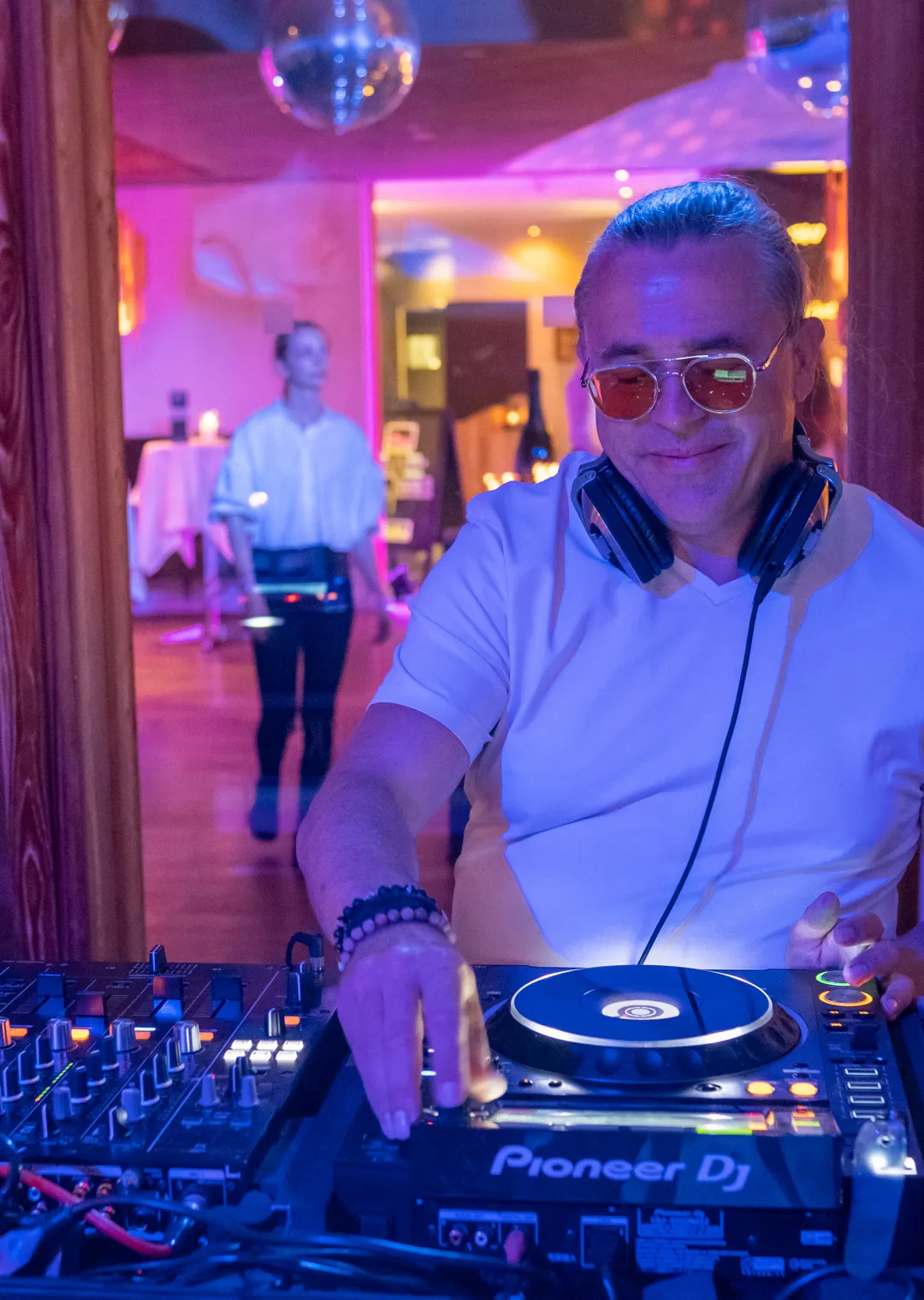 DJ legt Musik auf, bunte Beleuchtung im Hintergrund