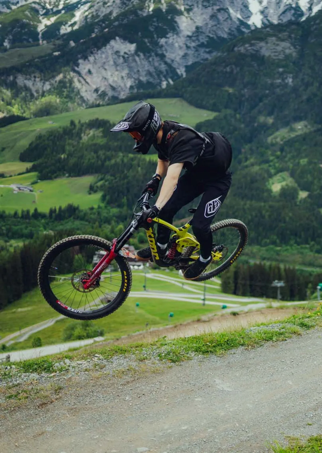 Mountain biker jumps over a path in the mountains.