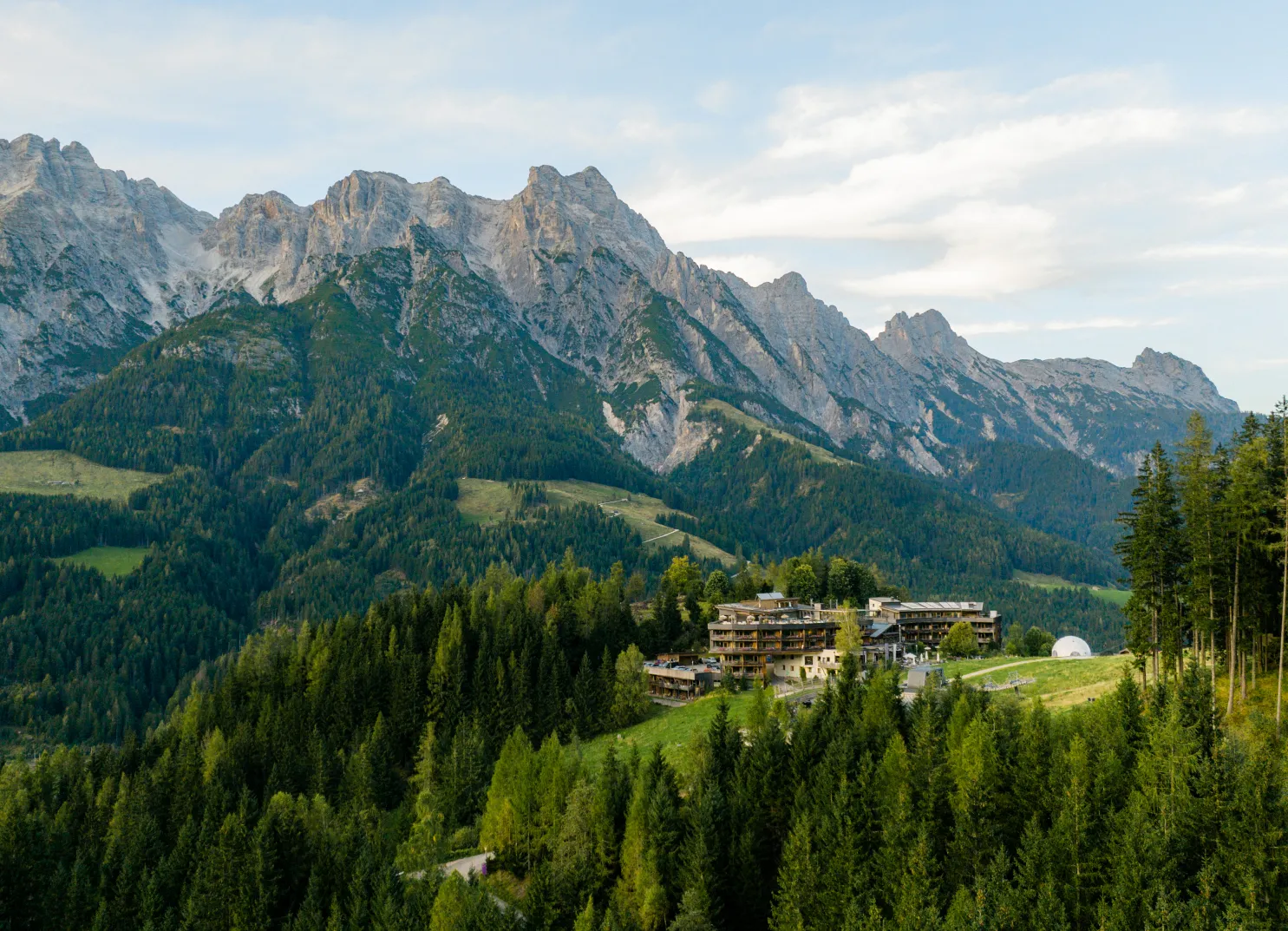 Berglandschaft mit Almen und einem Hotel im Vordergrund