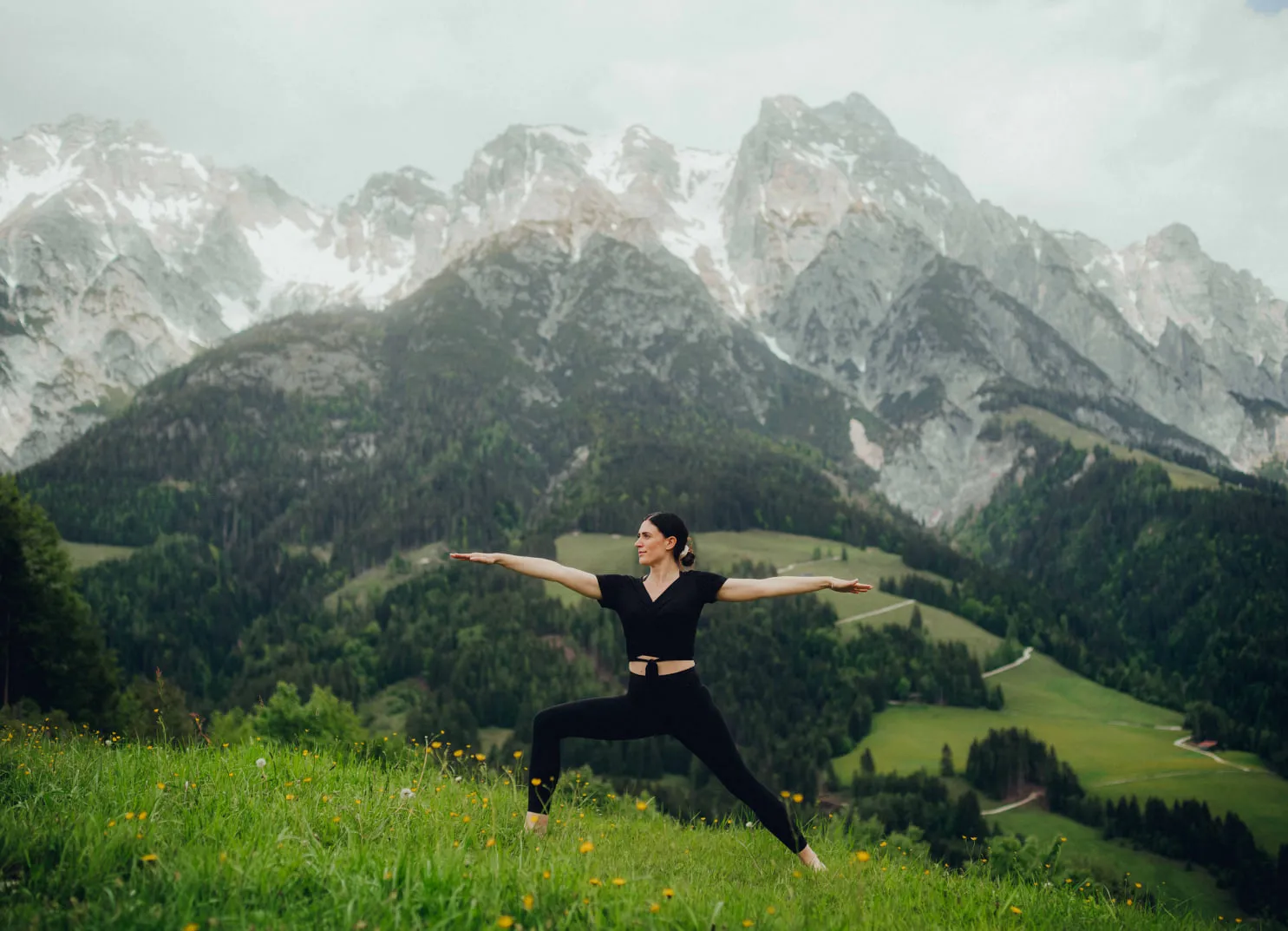 Frau in Yoga-Pose vor bergiger Landschaft.