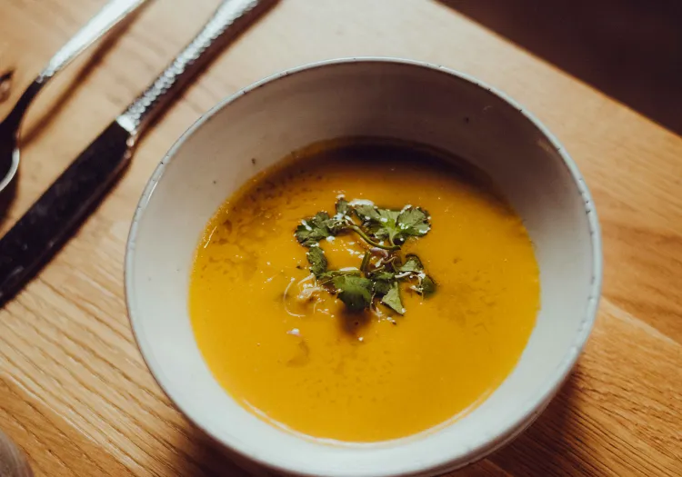 Kürbiscremesuppe in einer Schüssel auf einem Holztisch